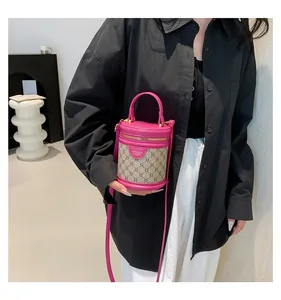 Detail of fuchsia leather and monogram canvas bucket bag shown on a model