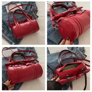 Detail view of red cylinder bag featuring stylish bow accents and versatile straps