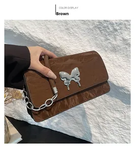 Detail view of brown pleated faux leather shoulder bag with a silver butterfly buckle