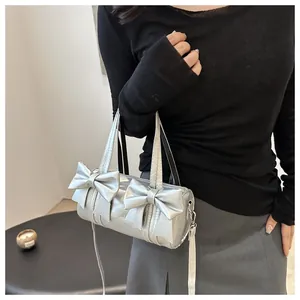 Detail of silver cylindrical handbag featuring 3D bows and fashion text on metallic surface