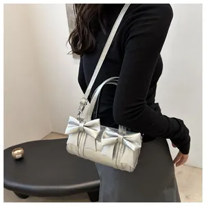 Detail of silver metallic handbag with bow accents and adjustable shoulder strap for women