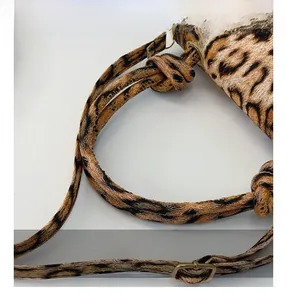 Detail of leopard print fabric strap with stylish knot design and gold metal buckle