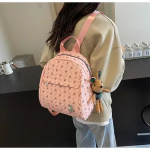 Pink mini backpack with rabbit prints and cute plush charm shown on model's back