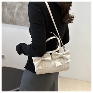 Detail view of cream white pleated hobo bag featuring decorative chic 3D bows