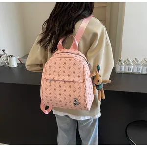 Close-up of pink leather backpack featuring rabbit prints and a brown plush bunny charm
