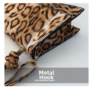 Detail of leopard print handbag showing the glossy gold metal hardware hook and neat stitching