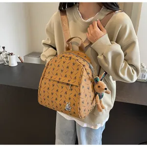 Detail of brown rabbit print backpack with plush charm worn by model in a cafe