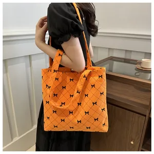 Détail du sac cabas en velours côtelé orange avec petits nœuds noirs et motif losange