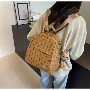 Detailed view of ginger yellow backpack with rabbit patterns and plush charm on a model