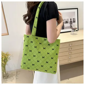 Détail du sac cabas en velours côtelé vert avec nœuds noirs et motifs à carreaux