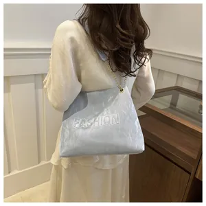 Détail du sac à bandoulière bleu clair avec texte en relief et chaîne dorée