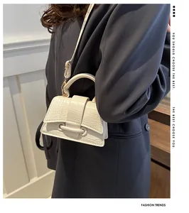 Chique crème mini-handtas van imitatie-krokodillenleer bij een grijze blazer