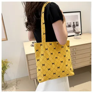 Détail du sac fourre-tout en velours côtelé jaune avec nœuds noirs et motif à carreaux