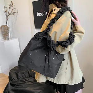 Black rivet tote bag with pleated shoulder strap styled with a trench coat