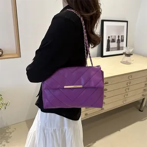 Deep purple quilted chain bag with V-stitch pattern worn over a model's shoulder