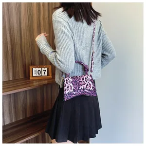 Close-up of leopard print shoulder bag featuring unique curved base and knotted handle