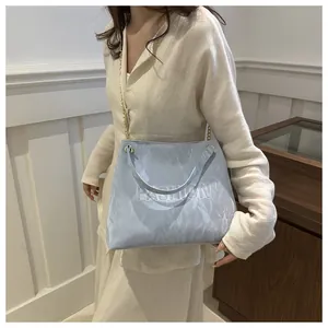 Détail du cabas bleu clair avec texte FASHION embossé et bandoulière chaîne dorée