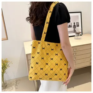 Détail d'un cabas en velours côtelé jaune avec motifs nœuds noirs et surpiqûres losanges