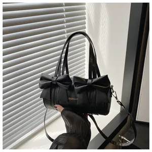 Detail shot of the large decorative bows and golden logo on the black cylinder bag