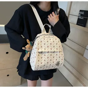 Detail view of beige backpack with brown rabbit prints and a plush animal keychain charm