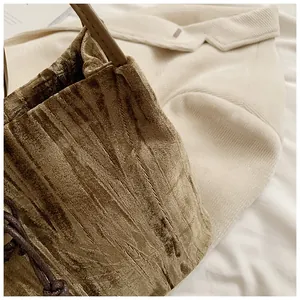 Macro detail of bronze pleated velvet tote bag with textured surface and woven drawstring