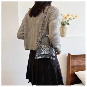 Leopard print crossbody bag with curved base and round top handle in an elegant setting