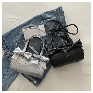 Detail of silver and black cylinder bags featuring large decorative bows and handles