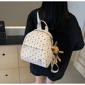 Detail of beige backpack with brown rabbit prints and a cute plush bunny charm hanging on side