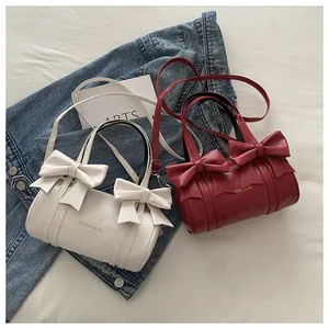 Detail of cylinder shoulder bags with bow ties in white and wine red colors