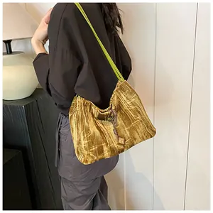 Detail of mustard yellow velvet shoulder bag with neon green strap on a model