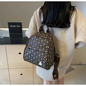Detail of dark brown mini backpack with golden rabbit monogram and white bunny pendant