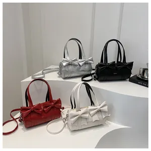 Group view of pleated cylinder bags with bow accents in silver, black, red, and white