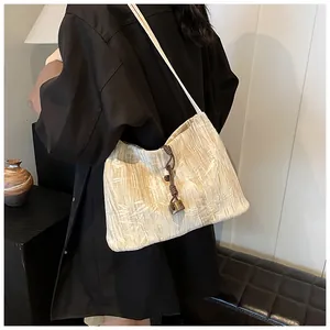 Detail of beige tote bag with bamboo leaf texture and braided strap on model