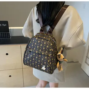Close-up of brown backpack with yellow bunny patterns and plush rabbit charm detail