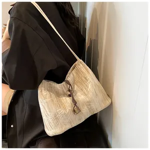 Detail of beige pleated fabric tote bag with brown woven knot and amber resin pendant