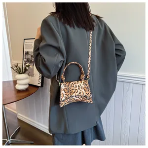 Detail of a leopard print mini handbag with curved base and elegant knotted top handle