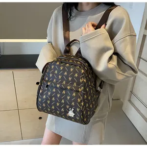 Detail view of brown monogram backpack with rabbit pattern and metallic charm on model