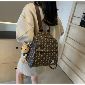 Detail view of brown faux leather backpack with rabbit patterns and plush bunny charm