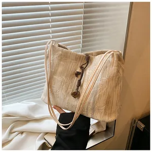 Detailed view of bamboo leaf jacquard texture and knotted charm on beige tote bag