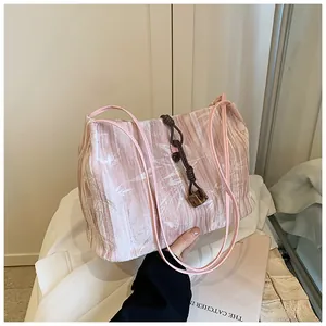 Detail of pink velvet tote bag featuring bamboo leaf patterns and decorative charm