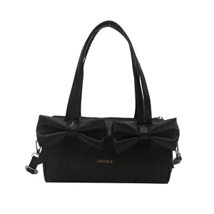 Black cylinder tote bag with large double bows and gold fashion lettering for women
