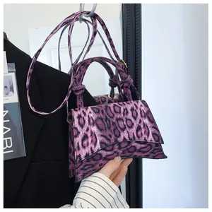 Detail view of purple leopard print crossbody bag with curved base and smooth handle