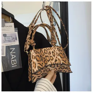 Detail shot of leopard print handbag with unique curved base and tied handle design