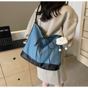 Detailed view of blue denim tote bag with leather bottom and cute cloud charm accessory