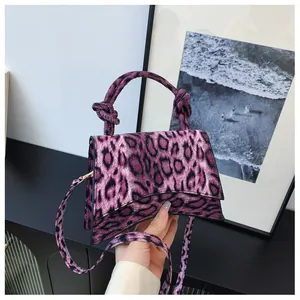 Detail of purple leopard print handbag featuring knotted handle and asymmetrical shape