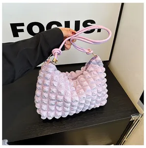 Detail of light purple pleated bag showing square bubble texture and knotted shoulder strap
