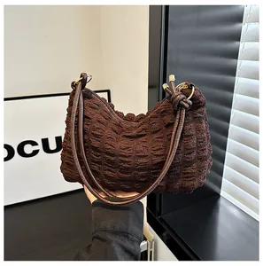 Macro detail of dark brown bubble textured fabric and golden zipper on shoulder bag