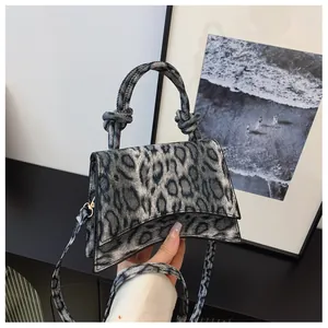 Detailed view of leopard print handbag with unique curved base and knotted handle detail