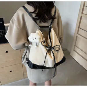 Detail of canvas backpack with contrast bow and plush cloud charm on model
