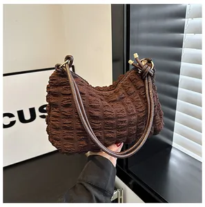 Close-up of deep brown pleated fabric underarm bag with slim leather straps and knots